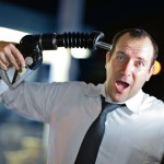 Businessman putting gas nozzle to his head, screaming.